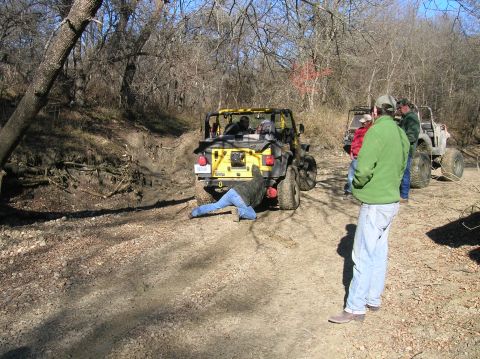 1996 Ford Bronco - A group of off-road vehicles navigate a muddy trail, with one Jeep requiring attention from underneath.