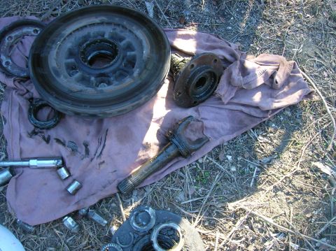 1996 Ford Bronco - Various automotive parts, including a brake drum and hub assembly, are laid out on a cloth on the ground.