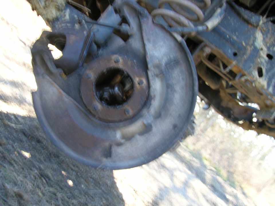 Front wheel hub assembly with exposed grease and rusty brake dust shield