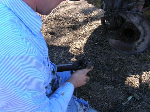 1996 Ford Bronco - Working on a vehicle's suspension part, possibly a brake assembly or axle component.