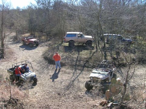 1996 Ford Bronco - A group of off-road vehicles are gathered in a natural, wooded setting.
