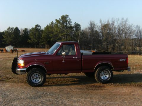 1992 Ford F-150 - A maroon 1992 Ford F-150 pickup truck is parked on a dirt road with a rural background.
