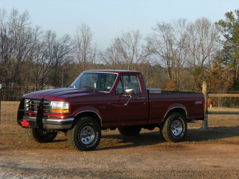 1992 Ford F-150 - Dark red Ford F-150 regular-cab short-bed 4x4 photographed from the front-left three-quarter angle in a fenced pasture with bare winter tre…