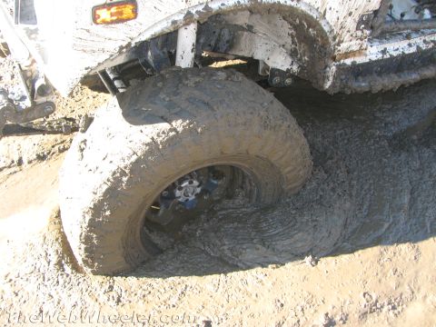1987 Suzuki Samurai - This vehicle is stuck in thick mud, with its tire deeply embedded.