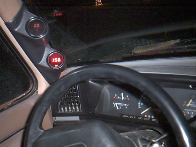 Truck interior at night with two red digital gauges on A-pillar pod above factory cluster