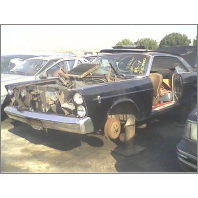 1972 Ford Ranchero - This car is in a junkyard, missing its hood and front wheels, with its doors open.
