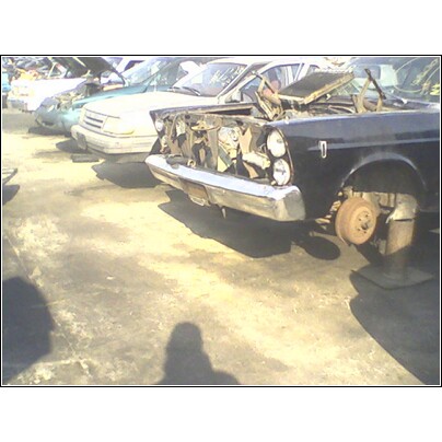 1972 Ford Ranchero - A black 1972 Ford Ranchero sits in a junkyard with its front end damaged and missing parts.