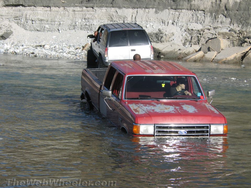 Red pickup truck and silver SUV driving through water