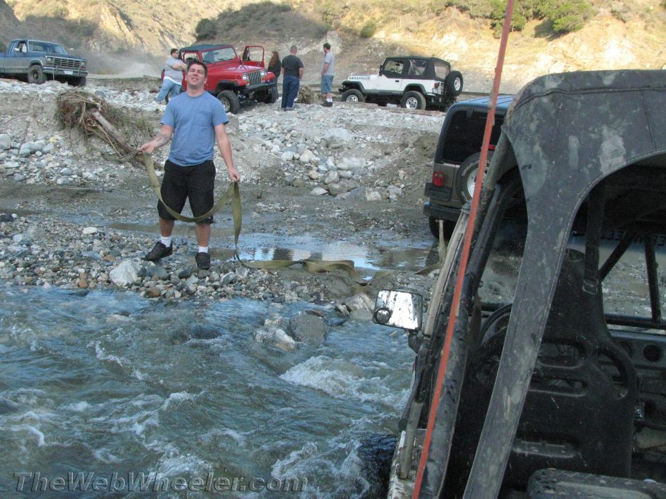 1987 Suzuki Samurai in a rocky stream bed with people and other off-road vehicles