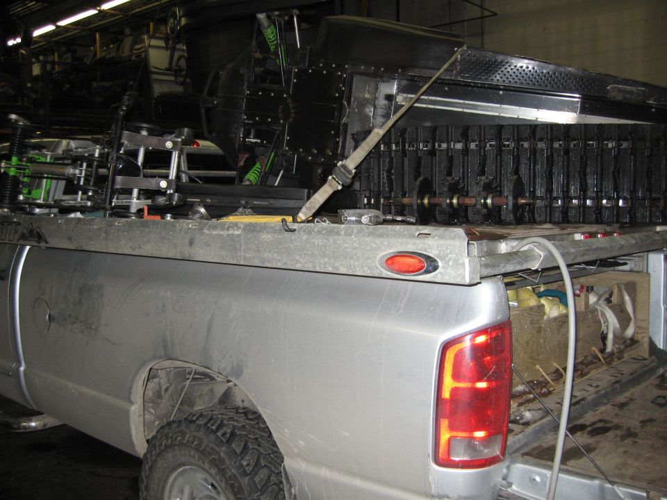 Silver pickup truck loaded with disassembled snowmobile parts in a shop