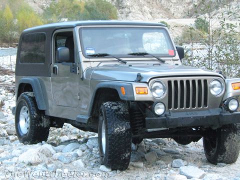 1987 Suzuki Samurai - A gray Jeep Wrangler with a black soft top is positioned on a rocky, off-road path.