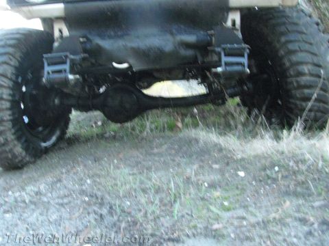 1987 Suzuki Samurai - The rear axle and large tires of an off-road vehicle are visible in this close-up shot.