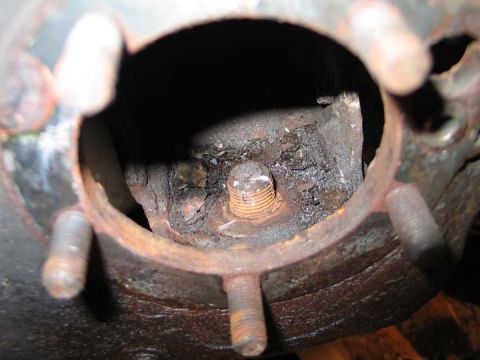 1994 Ford Bronco - Close-up view of a heavily rusted wheel hub assembly, showing a central bolt and surrounding studs.