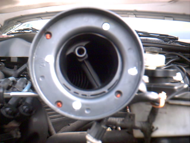 Close-up of a car's air intake housing, showing the circular opening and internal components