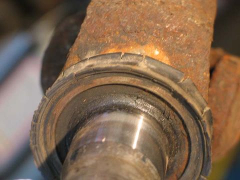 1994 Ford Bronco - A close-up view of a corroded vehicle hub assembly, showing wear on the rubber seal.