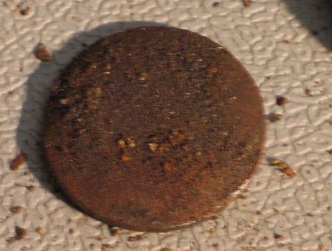 1994 Ford Bronco - A close-up view of a rusty, circular metal part resting on a textured surface.