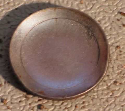 1994 Ford Bronco - A close-up view of a worn metal wheel hub cap.