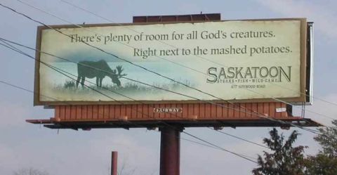 1998 Ford Crown Victoria - Billboard advertises Saskatoon Steaks Fish Wild Game with a moose graphic and slogan.