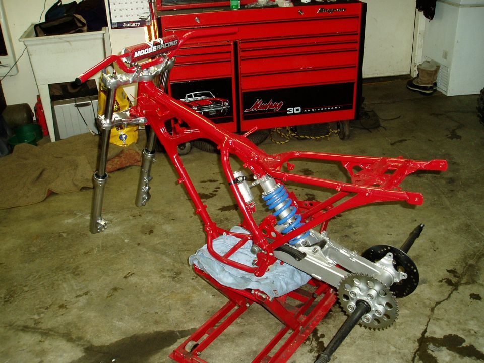 Red motorcycle frame with blue shock absorber on a red lift