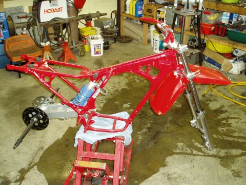 2000 Ford E350 - A red motorcycle frame is disassembled and supported by a red stand in a workshop.