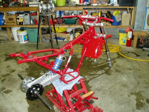 2000 Ford E350 - A red motorcycle frame is disassembled and placed on a lift in a workshop.