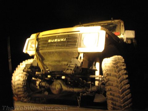 1987 Suzuki Samurai - Front view of a 1987 Suzuki Samurai at night, illuminated by its headlights.