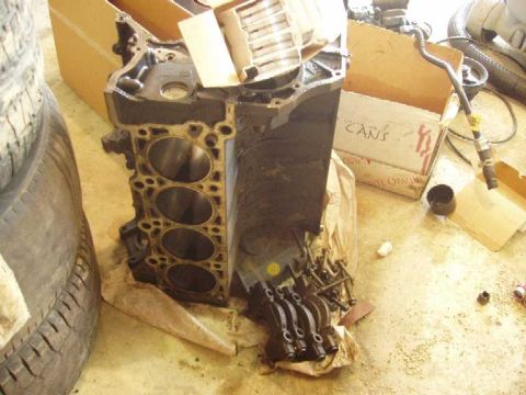 1996 Ford Crown Victoria - Engine block and associated parts are laid out on the floor next to a tire and cardboard boxes.