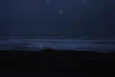1993 Ford Bronco - A dark, hazy scene of ocean waves under a dim sky, with several bright circular lights visible.