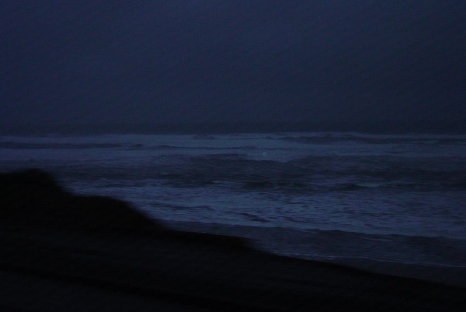 Ocean waves crashing on a dark beach at dusk