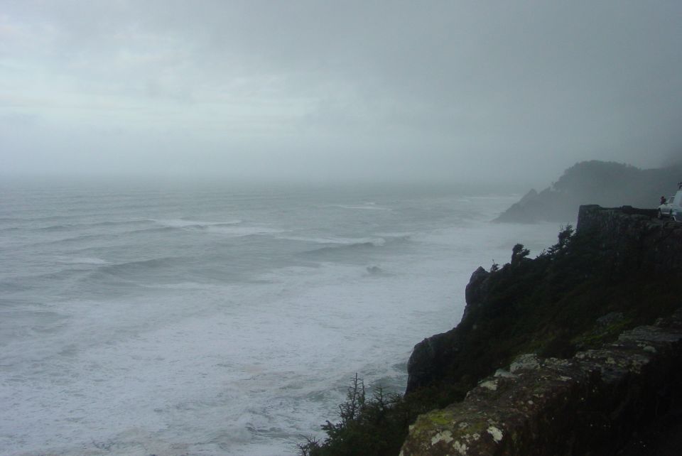 Ocean waves crash against a rocky cliffside under a cloudy sky. A watermark reads SUPERMOTORS.NET