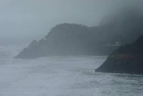 1993 Ford Bronco - A lighthouse stands on a rocky cliff overlooking a turbulent sea on a foggy day.