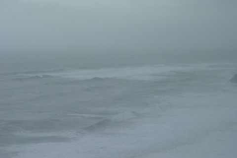 1993 Ford Bronco - The ocean is rough with waves breaking under a hazy sky.