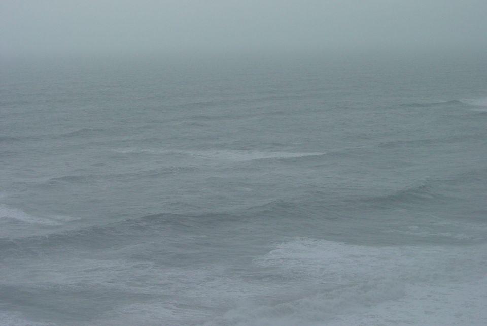 Ocean waves under a foggy sky. "SUPERMOTORS.NET" logo in the lower right corner
