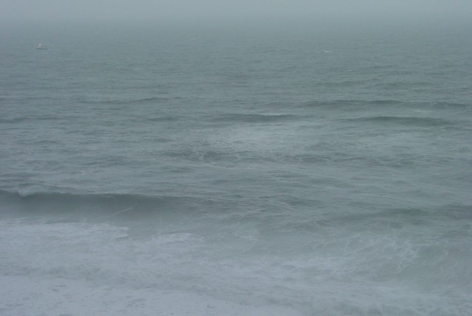 Ocean waves crashing on a foggy day. Supermotors.net logo in the corner