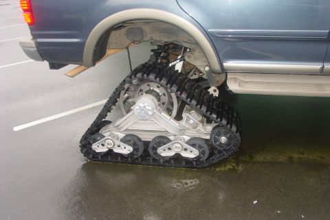 1993 Ford Bronco - Vehicle equipped with tank treads instead of rear wheels, seen from the side. Supermotors.net logo present.