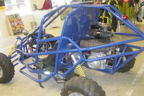 1993 Ford Bronco - A blue dune buggy with a roll cage and exposed engine is parked indoors.