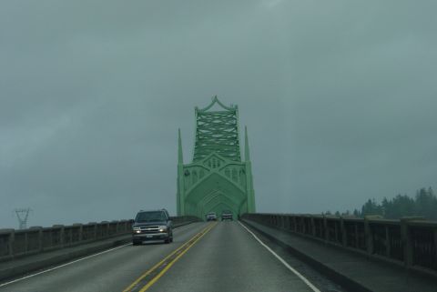 1993 Ford Bronco - A black SUV travels across a bridge under a cloudy sky, with a distinctive green bridge tower ahead.