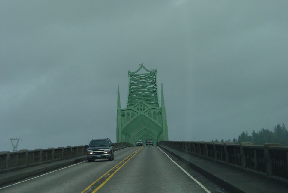 Black SUV driving on a bridge with a green gothic-style tower in the background