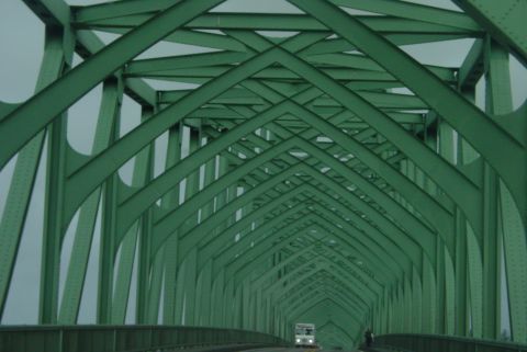 1993 Ford Bronco - A white truck is seen driving through a large green truss bridge.