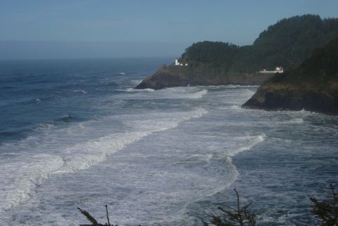 1993 Ford Bronco - A scenic view of the ocean with waves and a distant lighthouse on a cliffside.