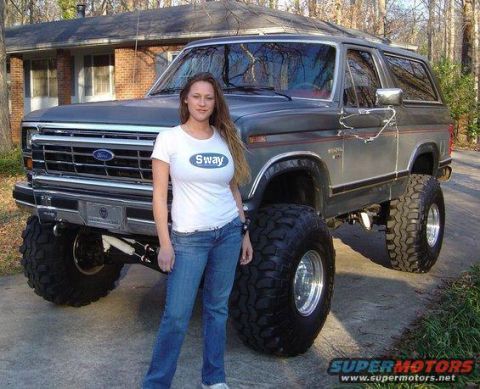 1970 Mercury Cougar - A woman stands next to a lifted Ford Bronco with oversized tires.