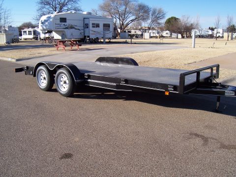 2004 Aston Martin Virage - A black dual-axle car trailer is parked in an outdoor lot with RVs in the background.