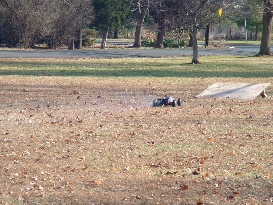 Radio-controlled car on dry grass near a wooden ramp