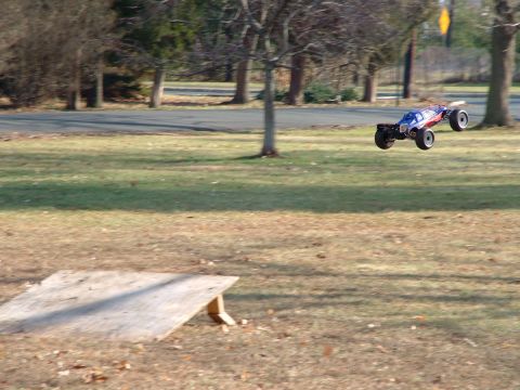 1994 Ford Bronco - A remote control buggy is captured mid-air, having launched from a ramp in a grassy park area.