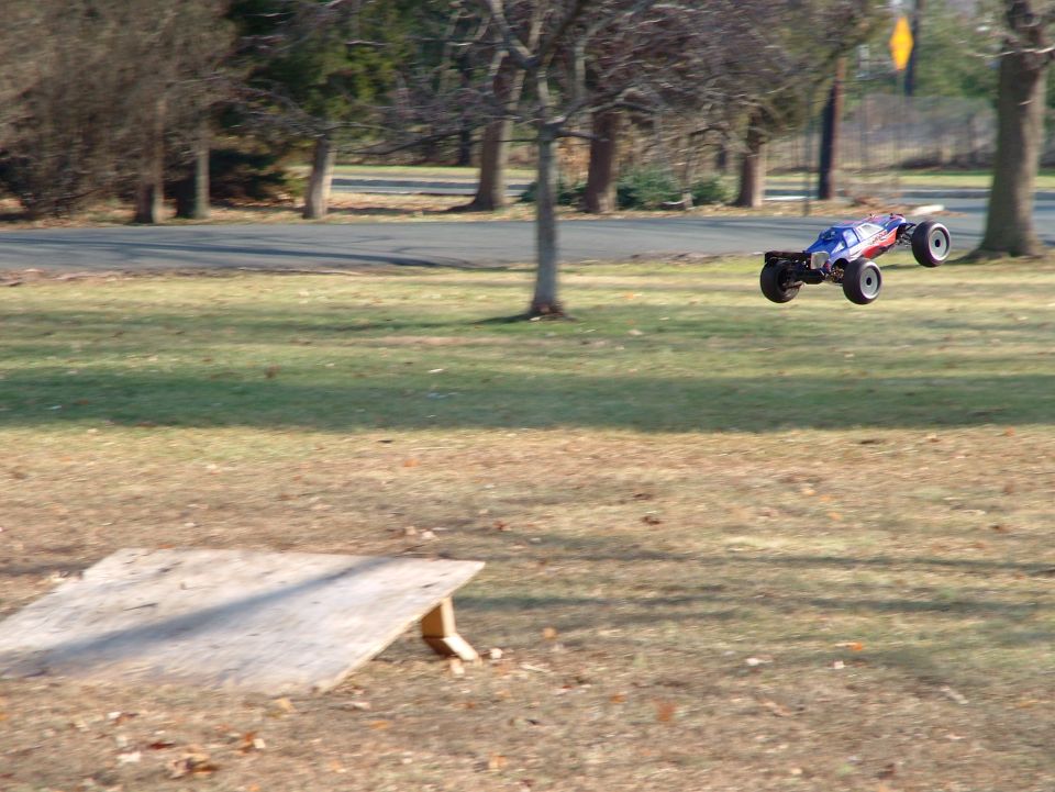 Remote control buggy airborne over grass, blue and red body