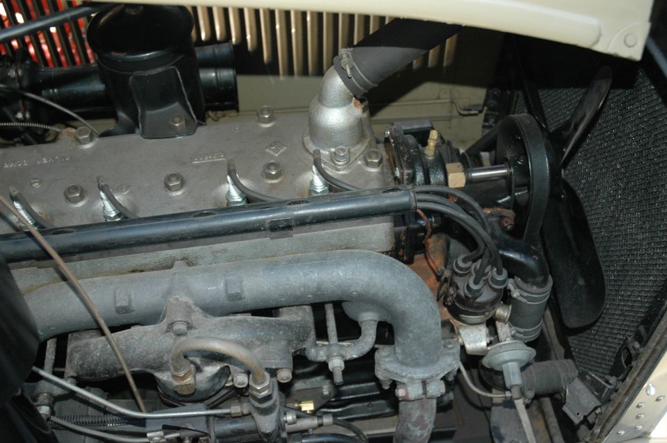 Vintage inline flathead engine with gray head, manifolds, fan and radiator