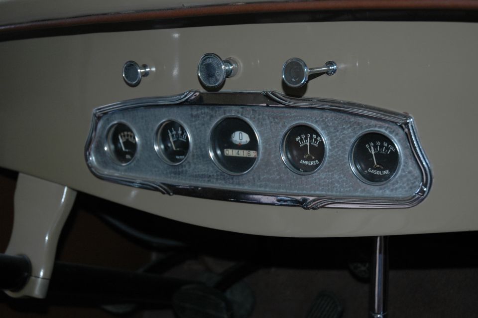Vintage cream dashboard with five chrome gauges and pull knobs, including AMPERES and GASOLINE meters.