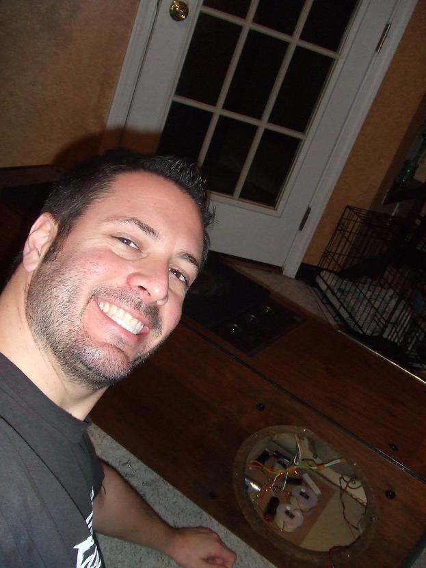 man smiling for selfie indoors, door and dog crate in background