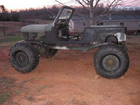 1980 Jeep CJ7 - This heavily modified Jeep sits on a custom chassis with oversized tires, appearing to be in a state of assembly or customization.