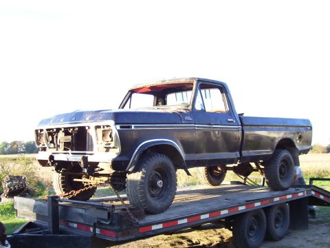 1979 Ford Pickup - A dark blue 1979 Ford pickup truck is loaded onto a flatbed trailer, missing its front grille.